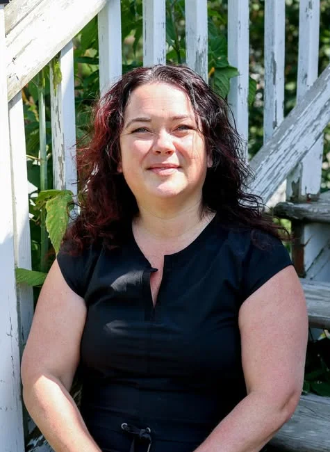 Jacinthe Dubois, souriante, assise dans un escalier extérieur